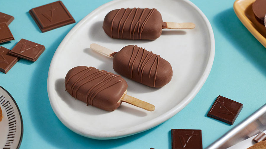 Several chocolate-covered ice cream pops displayed on a white plate, highlighting their rich, dark coating and frozen texture.